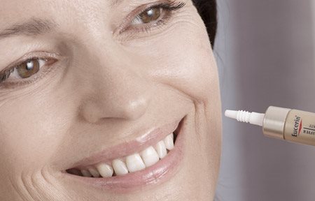 Donna che si applica il prodotto Eucerin sulla guancia sinistra