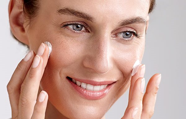 Donna che si applica la crema sulla guancia