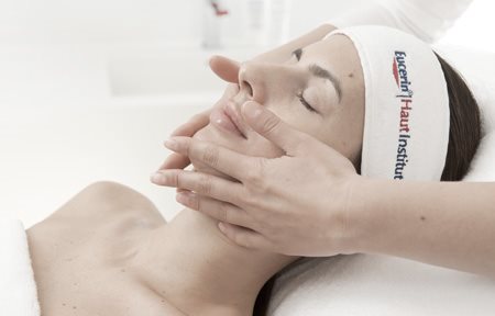 Viso di donna che viene toccato dalle mani del dermatologo