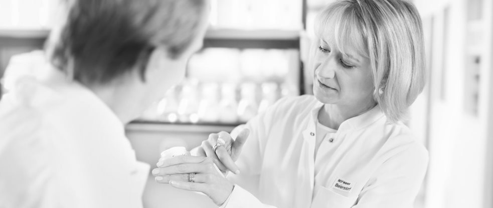 Scienziata donna che sta applicando la crema sulla parte superiore della mano - scienziato uomo che sta guardando.