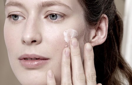 Donna che applica la crema sul viso