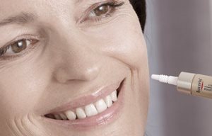 Donna che si applica il prodotto Eucerin sulla guancia sinistra