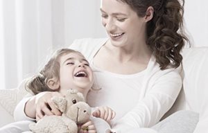 Madre che tiene fra le braccia il figlio - il bambino sta tenendo in mano un peluche.