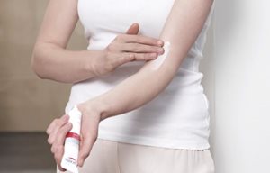 Donna che si applica Eucerin AtopiControl Crema Fasi Acute sulla piega del braccio