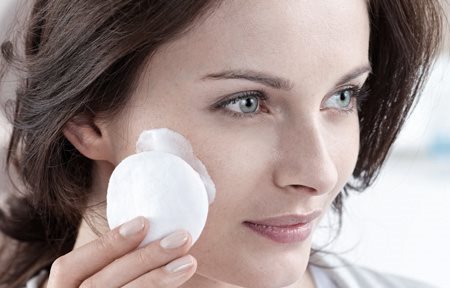 Donna che applica la crema con un batuffolo di cotone sul viso