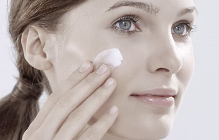 Donna con pelle sensibile che si applica la crema sul viso